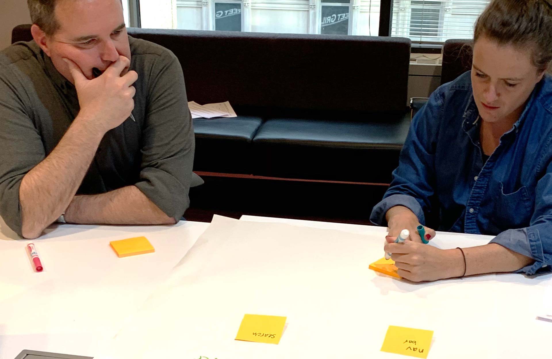Two Industry Dive executives collaborating over sticky notes during the 'Elevator pitch descriptors' exercise.